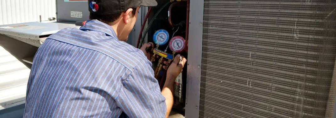HVAC technician servicing a condenser unit in Port Isabel